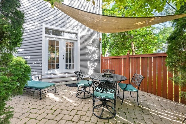 view of patio featuring french doors, fence, and outdoor dining area