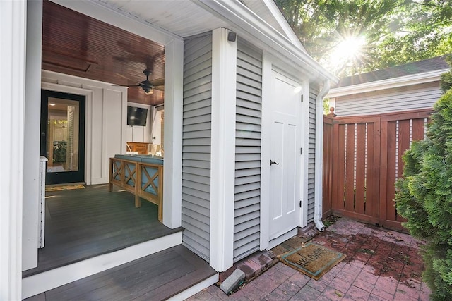 property entrance with a ceiling fan and fence