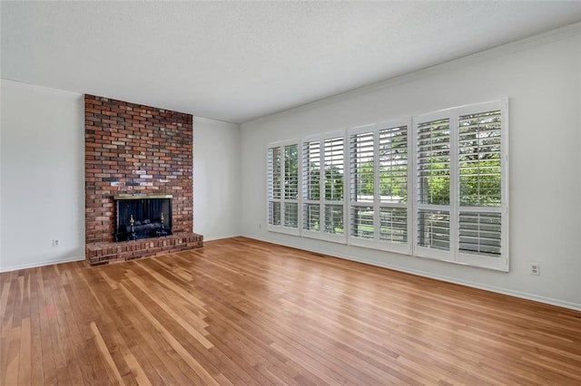 10014 Aldred Dr, Sunset Hills, MO 63128 - unfurnished living room with light wood-style floors, plenty of natural light, a textured ceiling, baseboards, and a brick fireplace