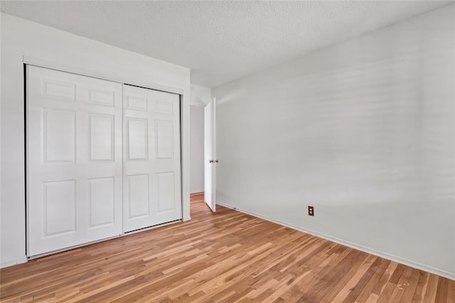 10014 Aldred Dr, Sunset Hills, MO 63128 - unfurnished bedroom with light wood-style flooring, a textured ceiling, a closet, and baseboards