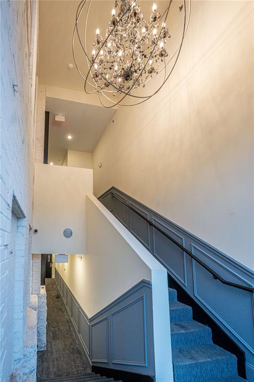 stairway with a chandelier, a towering ceiling, and wainscoting