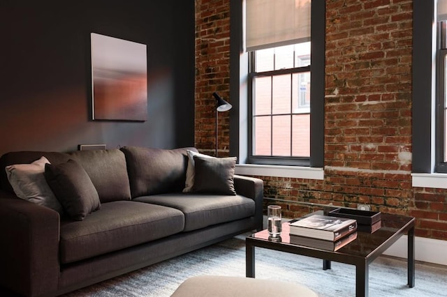 living area featuring brick wall and baseboards