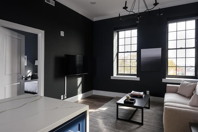 living room featuring wood finished floors, crown molding, baseboards, and a chandelier