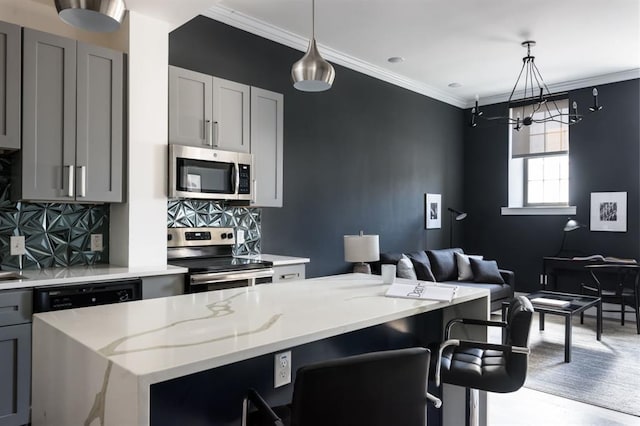 kitchen with appliances with stainless steel finishes, a chandelier, light stone countertops, gray cabinetry, and decorative backsplash