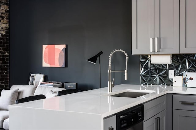 kitchen featuring a sink, gray cabinetry, dishwasher, light countertops, and backsplash