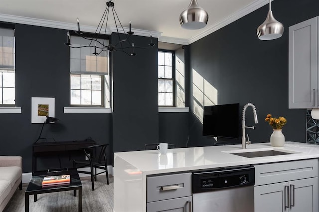 kitchen with dishwasher, a sink, ornamental molding, light countertops, and wood finished floors