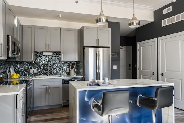 kitchen with appliances with stainless steel finishes, gray cabinetry, decorative backsplash, and crown molding