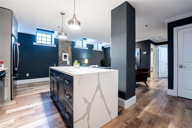 kitchen featuring light wood finished floors, decorative light fixtures, light stone countertops, baseboards, and a center island