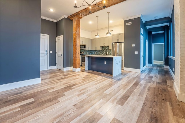 kitchen featuring stainless steel appliances, a center island, backsplash, crown molding, and light wood-type flooring