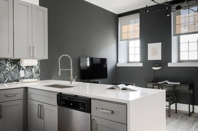 kitchen featuring dishwasher, a sink, a peninsula, gray cabinetry, and healthy amount of natural light