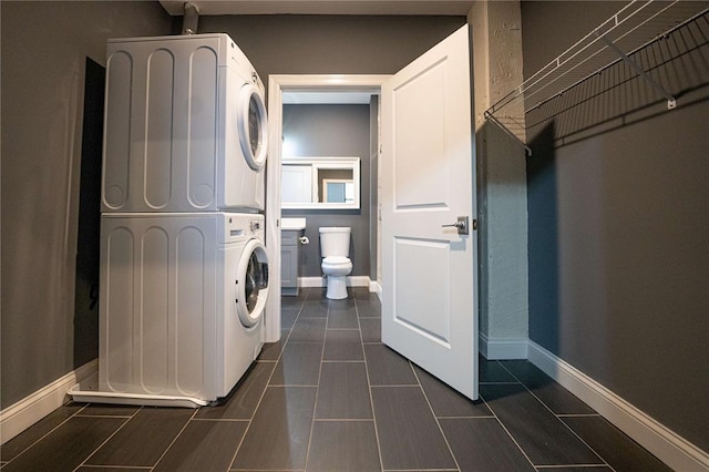 laundry area with estacked washer and dryer and baseboards