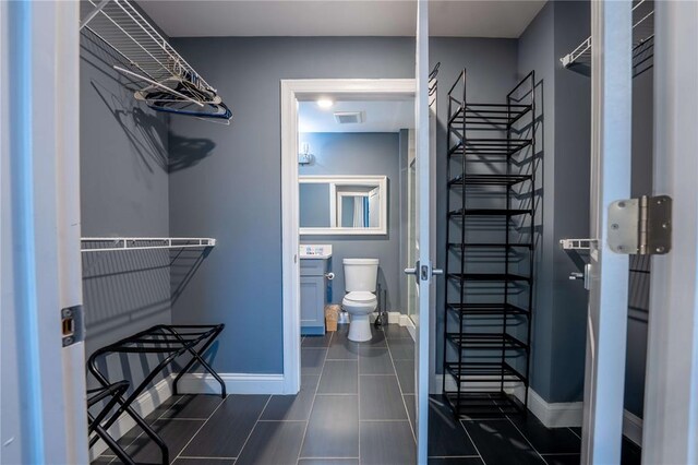 bathroom with toilet, baseboards, and tile patterned flooring