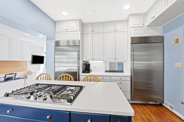 15 Briarcliff Rd, Ladue, MO 63124 - kitchen featuring appliances with stainless steel finishes, blue cabinetry, light countertops, wood finished floors, and recessed lighting