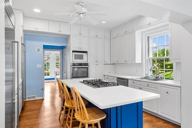 15 Briarcliff Rd, Ladue, MO 63124 - kitchen featuring stainless steel appliances, a sink, a kitchen breakfast bar, white cabinets, and light wood-style floors