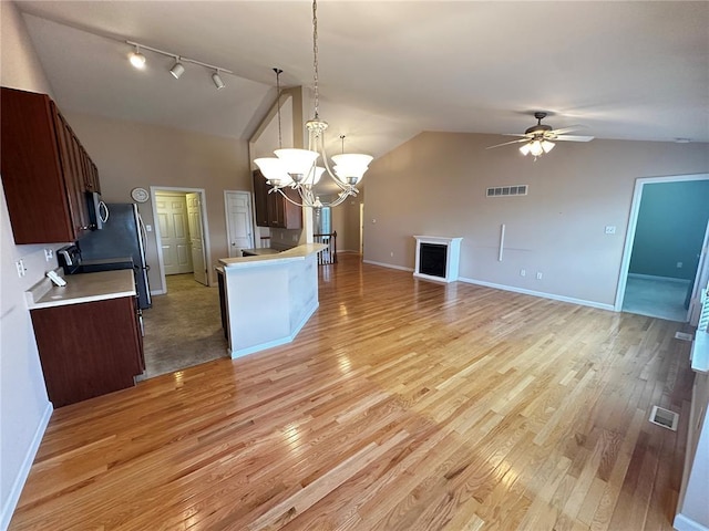 kitchen featuring open floor plan, a chandelier, light countertops, light wood-type flooring, and ceiling fan