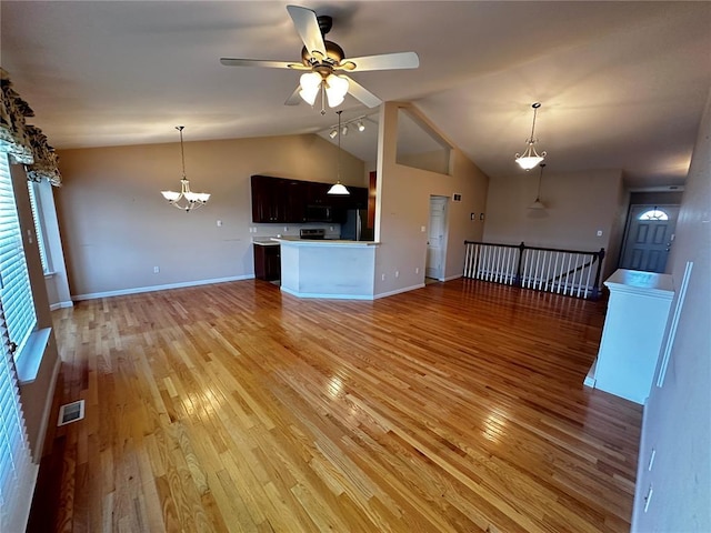 unfurnished living room with a ceiling fan, a chandelier, light wood finished floors, baseboards, and high vaulted ceiling