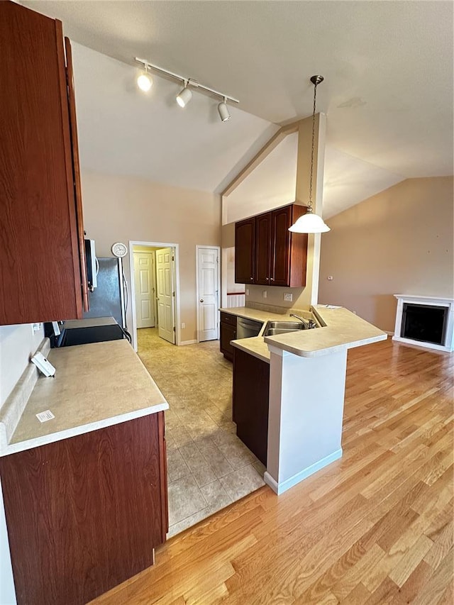 kitchen featuring light countertops, track lighting, vaulted ceiling, light wood-style flooring, and open floor plan