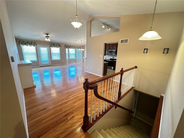 stairway with vaulted ceiling, wood finished floors, ceiling fan, and baseboards