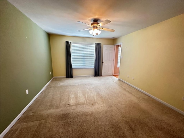 unfurnished room featuring carpet floors, a ceiling fan, and baseboards