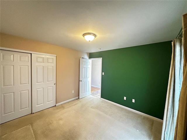 unfurnished bedroom with baseboards, light colored carpet, and a closet