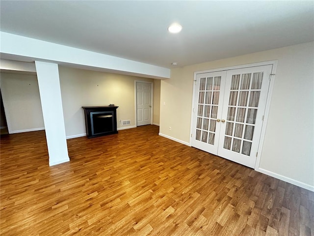 unfurnished living room with light wood finished floors, french doors, baseboards, recessed lighting, and a fireplace