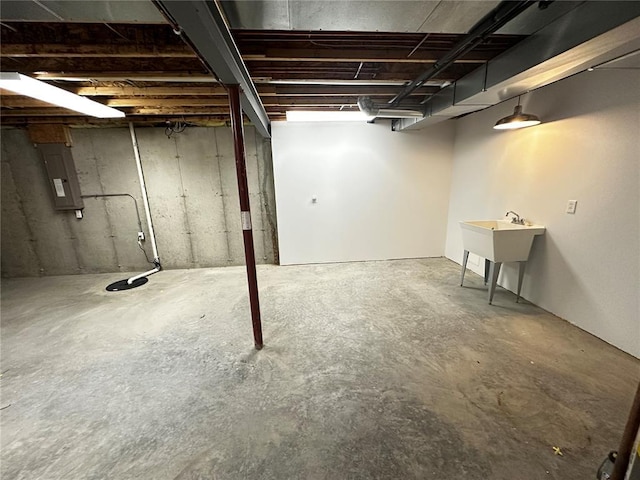 unfinished below grade area with electric panel and a sink