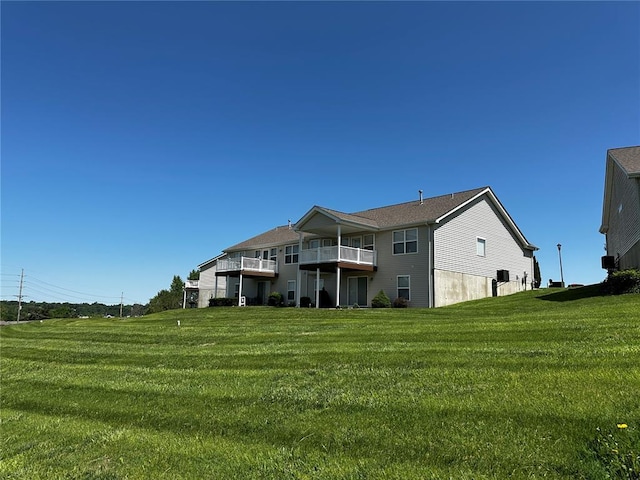 rear view of house featuring a lawn and a balcony