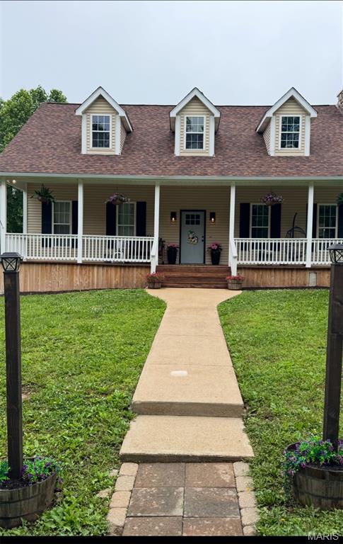 7011 Browns Ford Rd, Dittmer, MO 63023 - new england style home featuring a porch, a shingled roof, and a front lawn