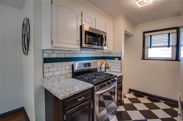 1104 Douglas St, Alton, IL 62002 - kitchen with appliances with stainless steel finishes, tile patterned floors, white cabinetry, decorative backsplash, and light stone counters