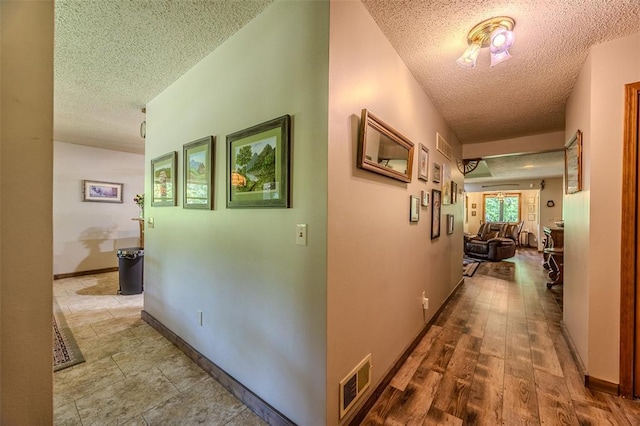 corridor featuring a textured ceiling and baseboards