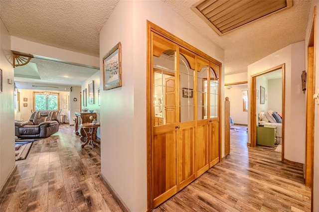 corridor with a textured ceiling and wood finished floors