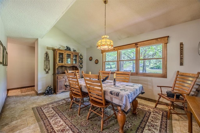 dining space with a textured ceiling, baseboards, and vaulted ceiling