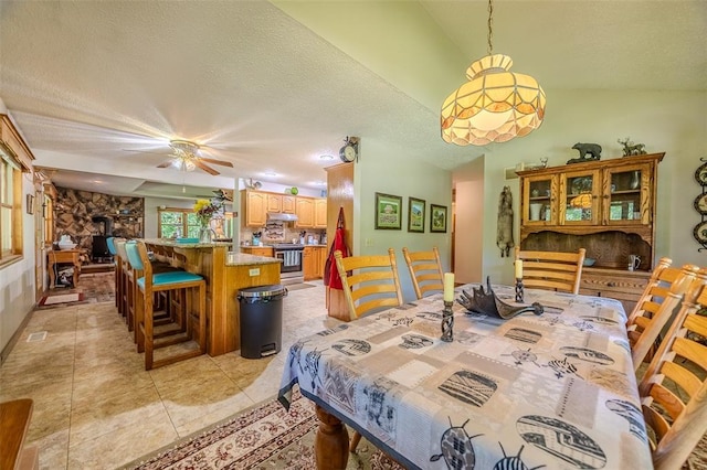 dining space featuring a textured ceiling, a ceiling fan, light tile patterned floors, and vaulted ceiling