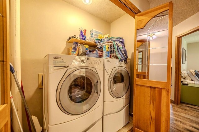 laundry room featuring separate washer and dryer, wood finished floors, and a textured ceiling