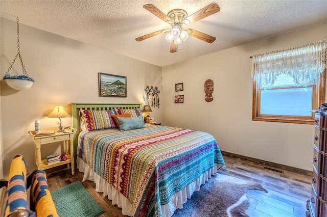 bedroom featuring wood finished floors, a ceiling fan, a textured ceiling, and baseboards