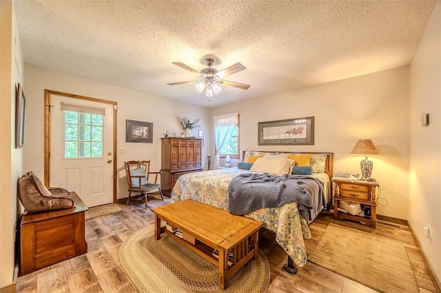 bedroom with a textured ceiling, light wood-style flooring, ceiling fan, and baseboards