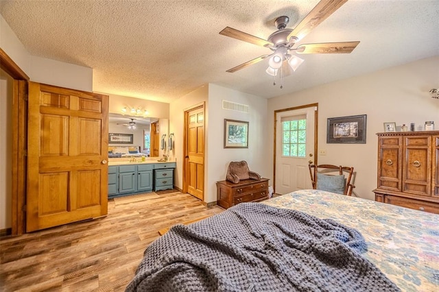 bedroom with light wood-style floors, a textured ceiling, ensuite bathroom, and ceiling fan