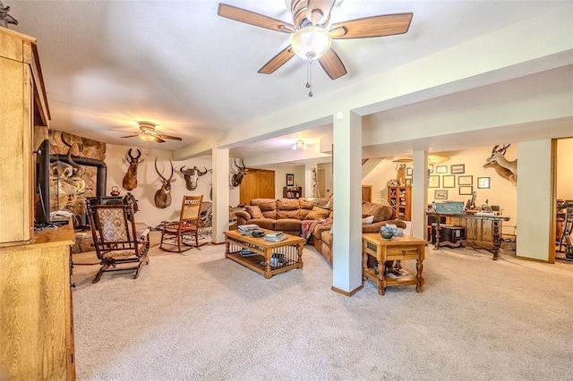 carpeted living room with a wood stove and a ceiling fan