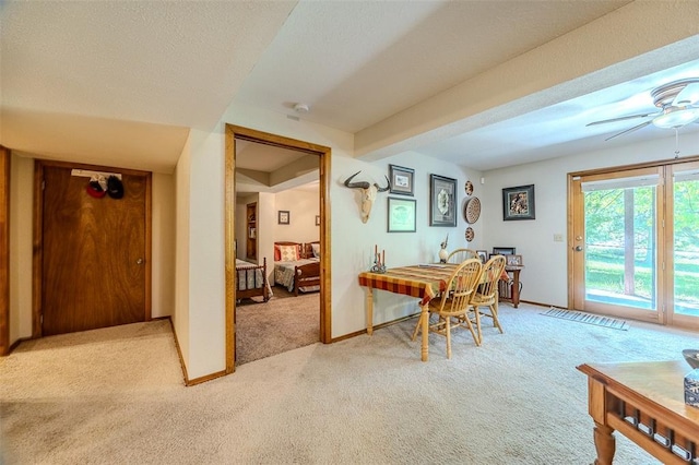 carpeted office space featuring a ceiling fan and baseboards