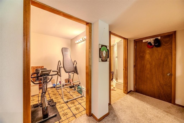 exercise room with baseboards and light carpet