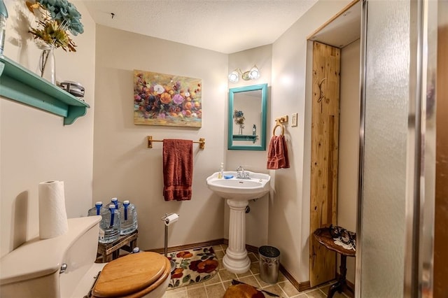 bathroom with toilet, tile patterned flooring, and baseboards