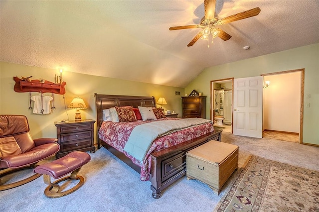 bedroom with light colored carpet, vaulted ceiling, a textured ceiling, ensuite bath, and a ceiling fan