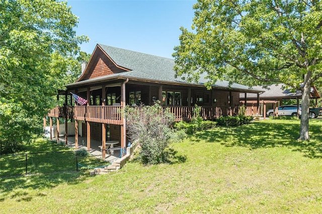 back of property featuring a carport, a deck, roof with shingles, and a patio