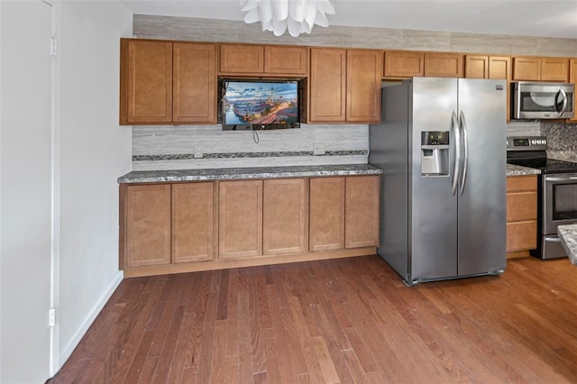 1404 Hampton Ct, Belleville, IL 62223 - kitchen with appliances with stainless steel finishes, backsplash, dark stone counters, brown cabinets, and dark wood finished floors