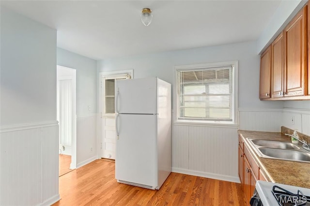 1321 Highmont Dr, Saint Louis, MO 63135 - kitchen with freestanding refrigerator, brown cabinets, light wood finished floors, a wainscoted wall, and range