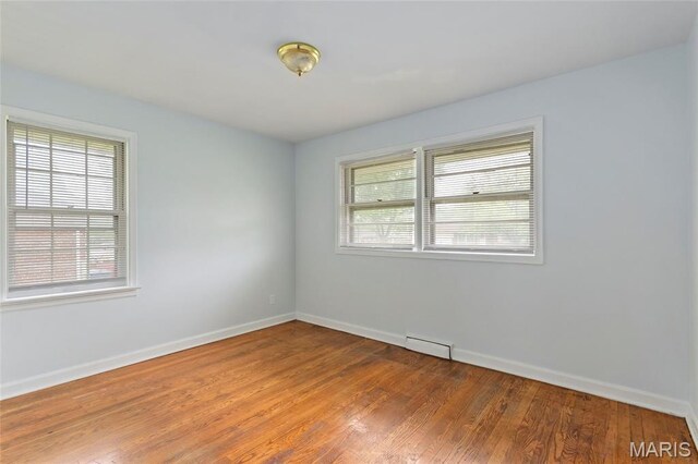 1321 Highmont Dr, Saint Louis, MO 63135 - empty room with healthy amount of natural light, wood finished floors, and a baseboard heating unit