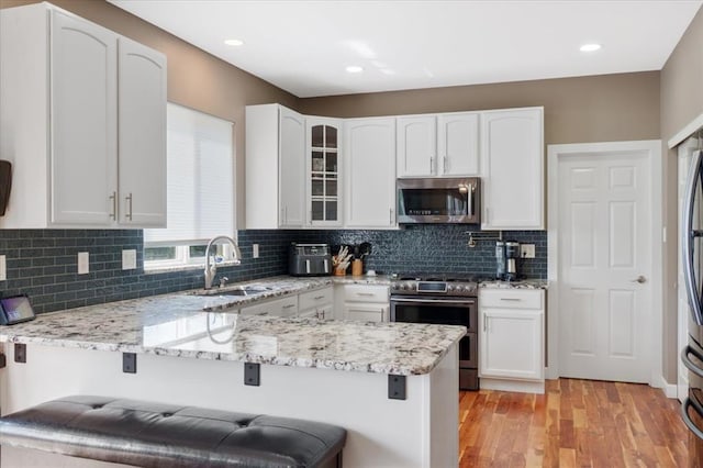 5 The Crossings Ct, Ofallon, MO 63366 - kitchen featuring stainless steel appliances, a sink, a peninsula, a breakfast bar area, and glass insert cabinets