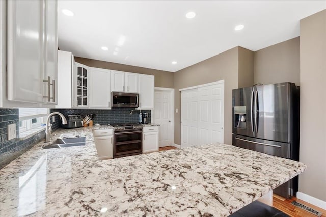 5 The Crossings Ct, Ofallon, MO 63366 - kitchen featuring stainless steel appliances, a sink, baseboards, a peninsula, and light stone counters