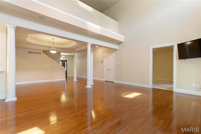 106 Tuscany Trace Dr, Saint Charles, MO 63303 - unfurnished living room with ornate columns, a raised ceiling, wood-type flooring, baseboards, and a high ceiling