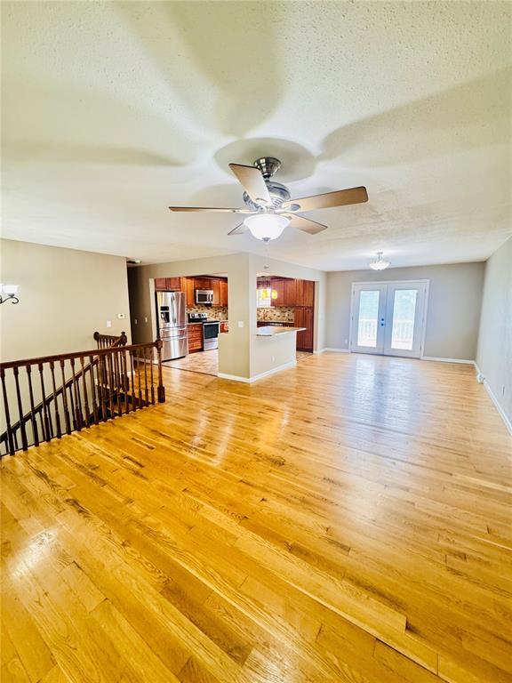 1202 S Mildred Ave, Salem, MO 65560 - unfurnished living room featuring ceiling fan, light wood-type flooring, a chandelier, a textured ceiling, and baseboards